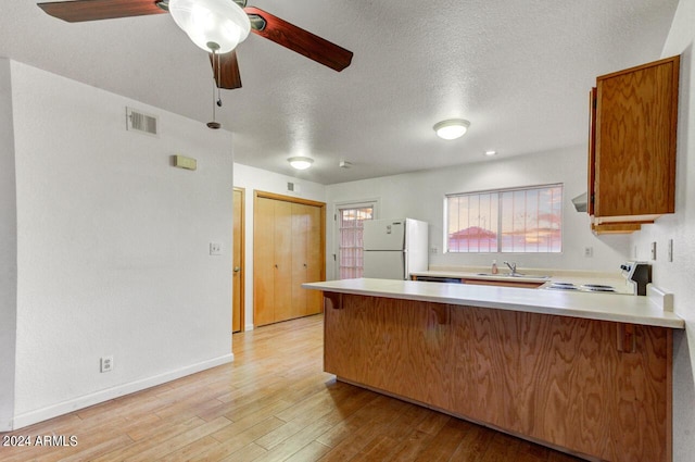 kitchen with light hardwood / wood-style flooring, a textured ceiling, electric range oven, kitchen peninsula, and white fridge