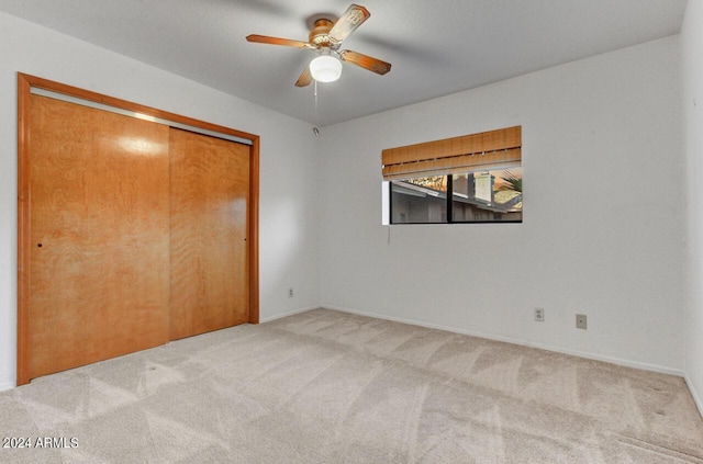 unfurnished bedroom with light carpet, ceiling fan, and a closet