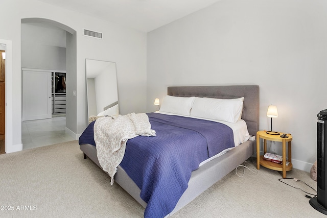 bedroom featuring arched walkways, visible vents, and carpet flooring