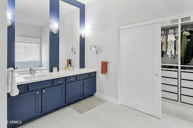 full bathroom with a sink, baseboards, a spacious closet, and double vanity