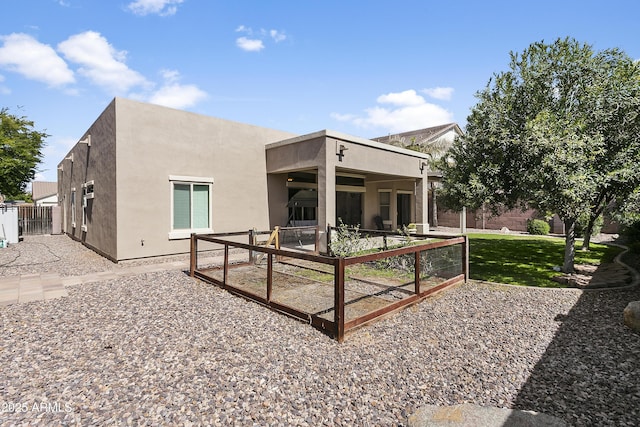 rear view of house featuring a patio, fence, and stucco siding