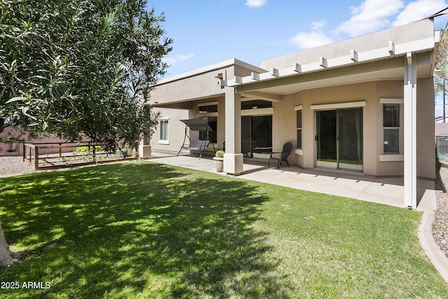 rear view of house featuring stucco siding, a yard, and a patio area