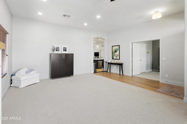 living room featuring visible vents, light carpet, recessed lighting, arched walkways, and baseboards