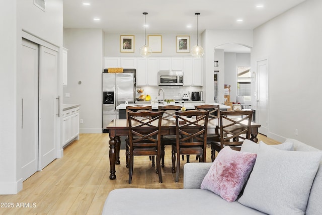 dining space featuring recessed lighting, visible vents, arched walkways, and light wood-style floors