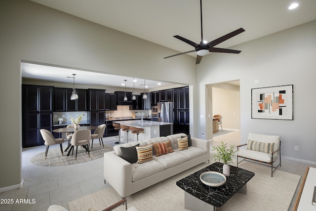 living room featuring ceiling fan, sink, light tile patterned floors, and high vaulted ceiling