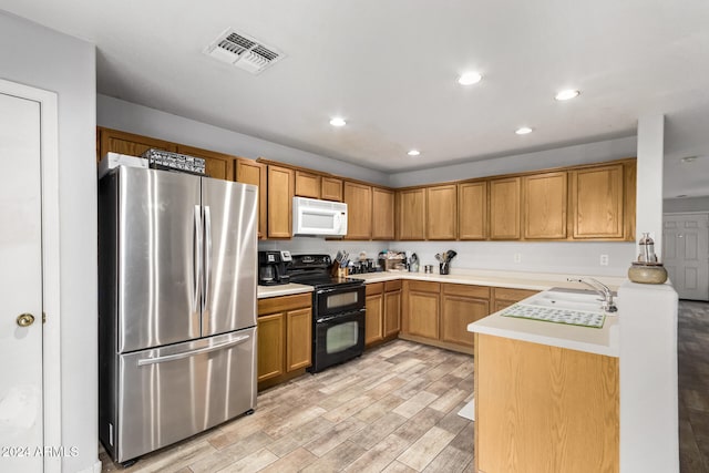 kitchen featuring stainless steel fridge, light hardwood / wood-style flooring, black electric range oven, and sink