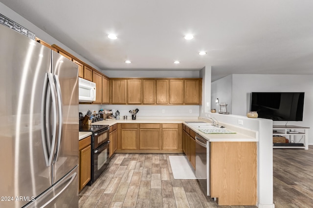 kitchen featuring kitchen peninsula, stainless steel appliances, hardwood / wood-style flooring, and sink