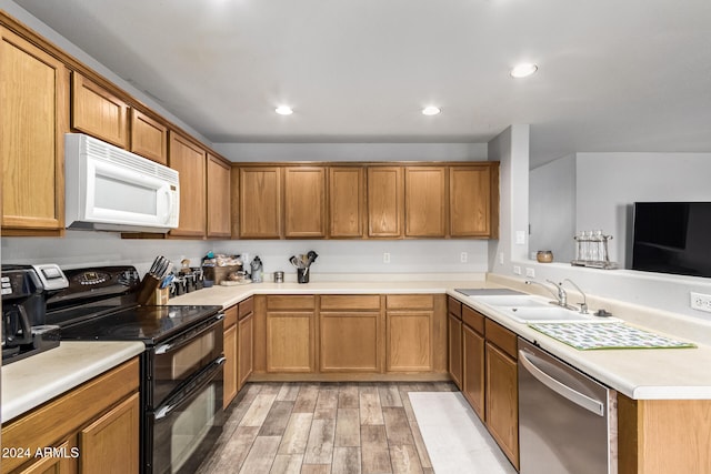 kitchen with light hardwood / wood-style floors, black range with electric stovetop, stainless steel dishwasher, and sink