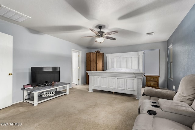 bedroom featuring light carpet, ceiling fan, and a textured ceiling