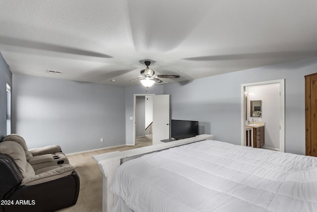 carpeted bedroom with a textured ceiling, ensuite bath, and ceiling fan