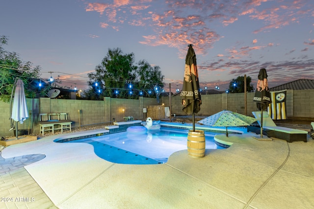 pool at dusk featuring a patio