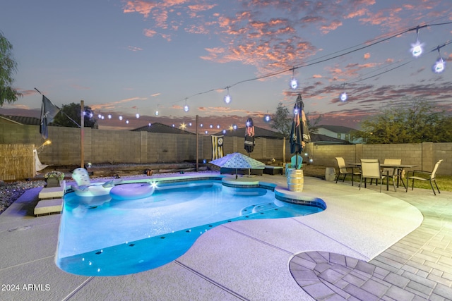 pool at dusk with a patio area