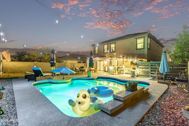 pool at dusk featuring a patio and area for grilling