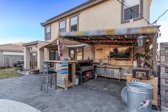 rear view of house with a wet bar and a patio