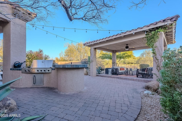 view of patio with ceiling fan, an outdoor living space, exterior kitchen, and a grill