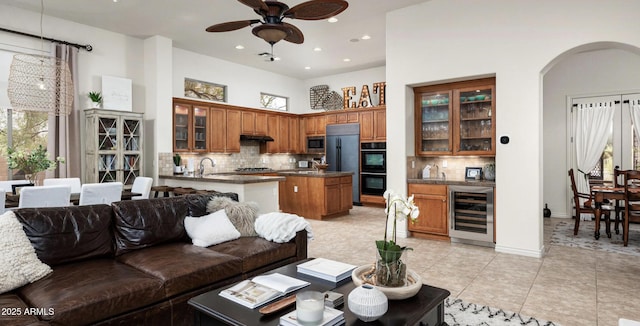 living room featuring ceiling fan, sink, light tile patterned floors, and wine cooler