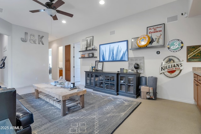 carpeted living room with ceiling fan and indoor bar