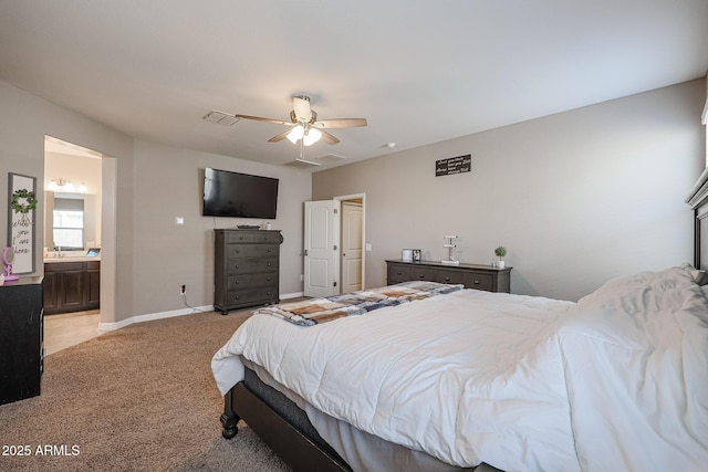 bedroom featuring connected bathroom, light colored carpet, and ceiling fan