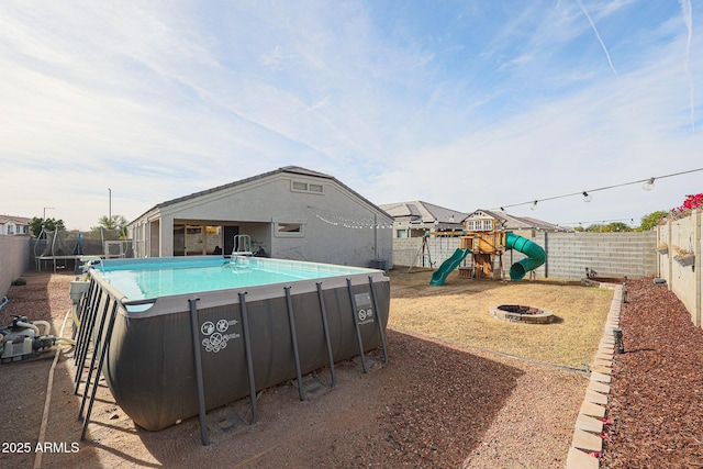 view of swimming pool featuring a trampoline, a fire pit, and a playground