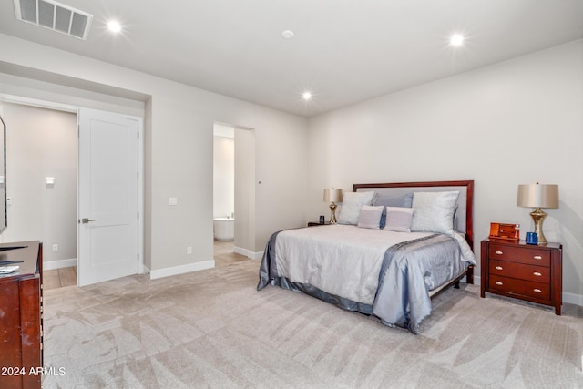 bedroom with light colored carpet and ensuite bathroom