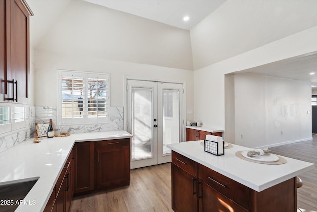 kitchen featuring lofted ceiling, light wood-type flooring, light countertops, and french doors