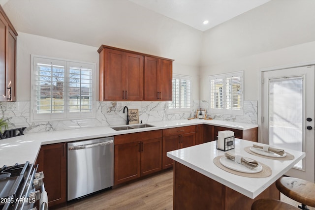 kitchen with decorative backsplash, a kitchen breakfast bar, stainless steel appliances, light countertops, and a sink