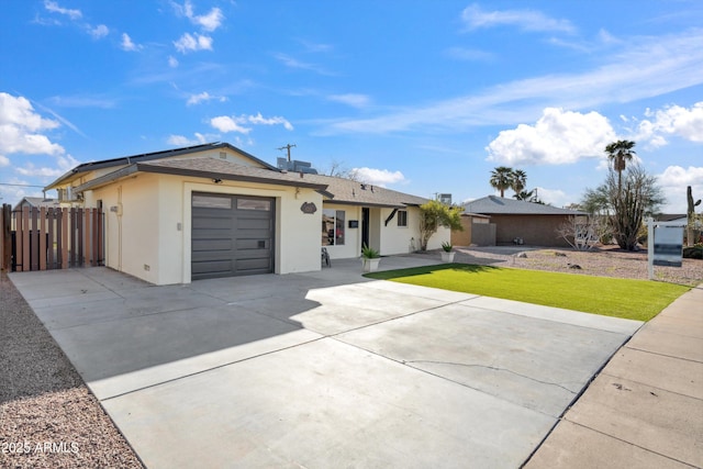 ranch-style home featuring driveway, an attached garage, fence, a front yard, and stucco siding