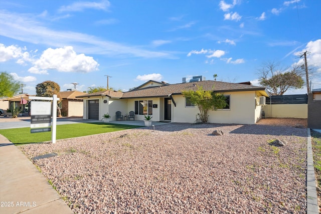 single story home with stucco siding, an attached garage, fence, driveway, and a front lawn