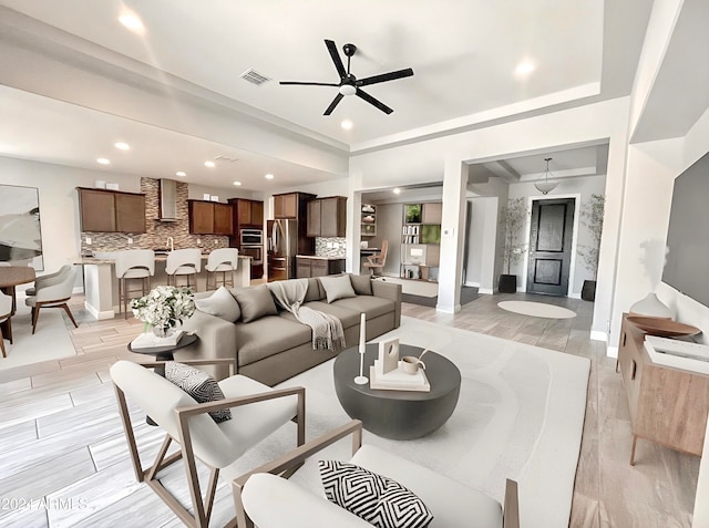 living room with crown molding, light wood-type flooring, and ceiling fan