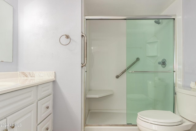 full bathroom featuring a stall shower, toilet, and vanity