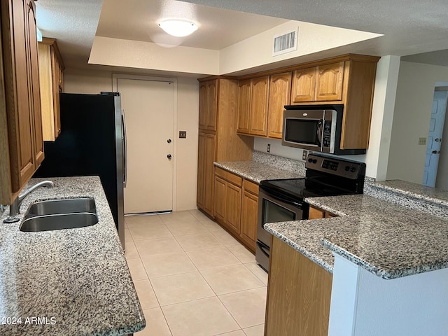 kitchen featuring kitchen peninsula, dark stone countertops, sink, and stainless steel appliances