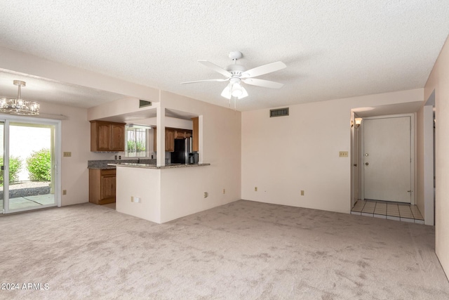 kitchen featuring light colored carpet, black fridge, ceiling fan with notable chandelier, visible vents, and brown cabinets