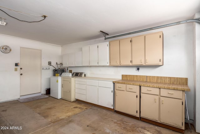 kitchen featuring washing machine and clothes dryer, concrete floors, light countertops, and cream cabinetry