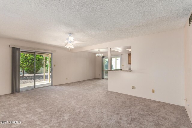 spare room with a notable chandelier, a textured ceiling, and carpet