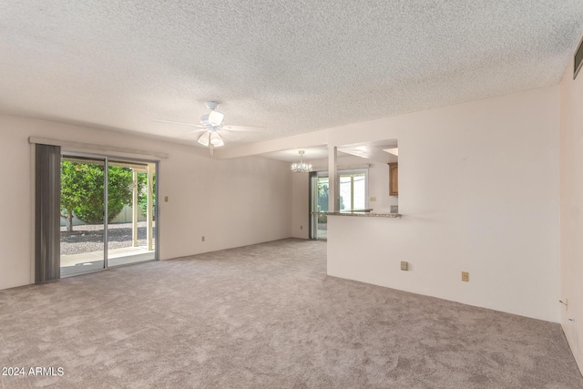 spare room with light carpet, ceiling fan with notable chandelier, and a textured ceiling