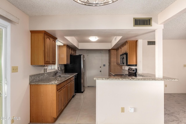kitchen with a sink, visible vents, stainless steel appliances, and light stone counters