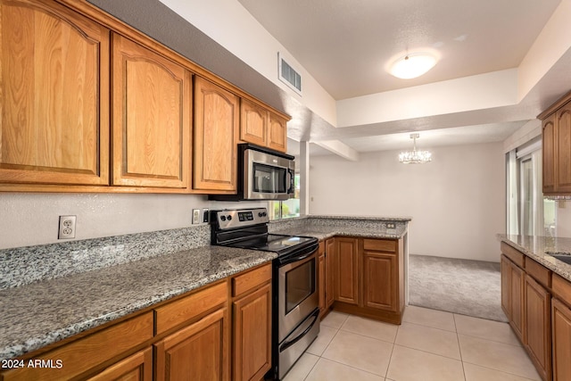 kitchen featuring visible vents, a peninsula, brown cabinets, stainless steel appliances, and stone countertops