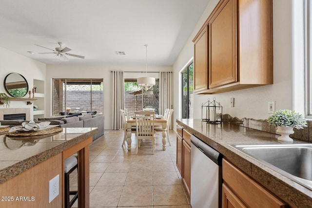3026 W Silver Fox Way, Phoenix, AZ 85045 - kitchen featuring stainless steel dishwasher, brown cabinets, a fireplace, a ceiling fan, and light tile patterned floors