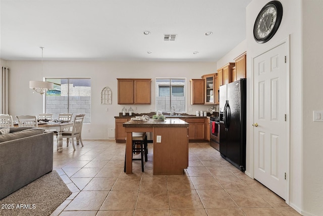 3026 W Silver Fox Way, Phoenix, AZ 85045 - kitchen featuring black fridge, open floor plan, a center island, dark countertops, and glass insert cabinets