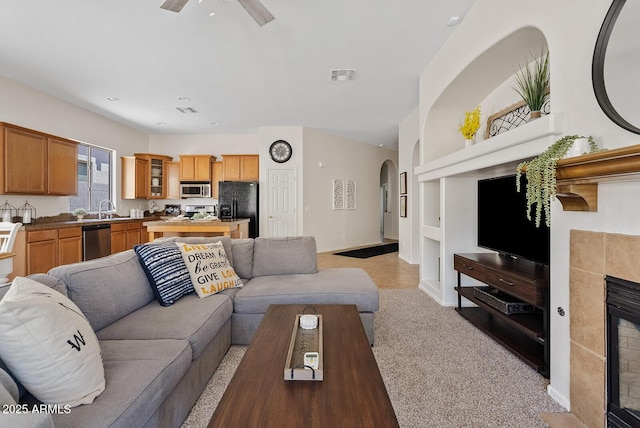 3026 W Silver Fox Way, Phoenix, AZ 85045 - living room with a tile fireplace, arched walkways, ceiling fan, light colored carpet, and built in shelves