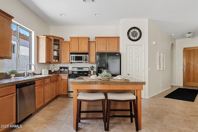 3026 W Silver Fox Way, Phoenix, AZ 85045 - kitchen featuring stainless steel appliances, a kitchen breakfast bar, glass insert cabinets, a kitchen island, and light tile patterned floors