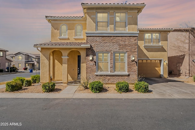 mediterranean / spanish home featuring a garage, a tile roof, driveway, and stucco siding