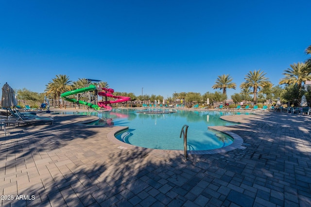 community pool featuring a water slide and a patio area