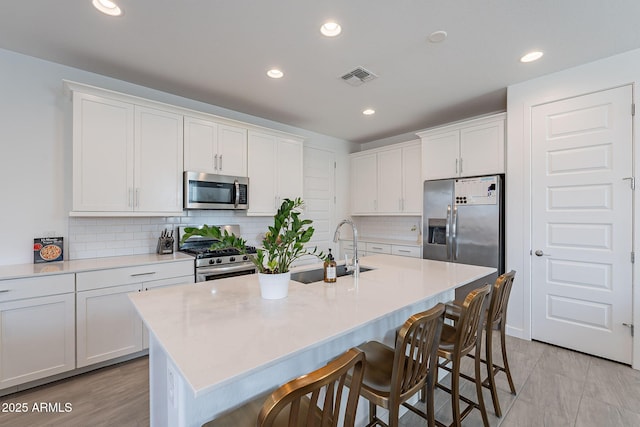 kitchen featuring visible vents, appliances with stainless steel finishes, white cabinets, and a sink