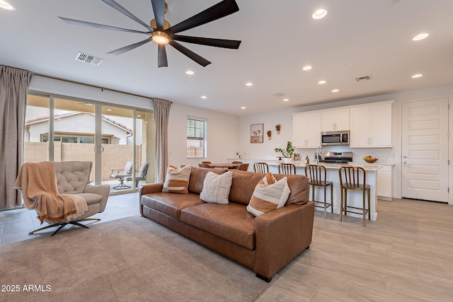 living area with a ceiling fan, recessed lighting, and visible vents