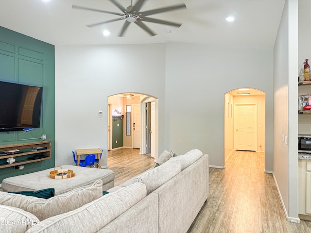 living room featuring light hardwood / wood-style flooring, high vaulted ceiling, and ceiling fan