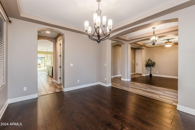 empty room with ceiling fan with notable chandelier and dark hardwood / wood-style floors