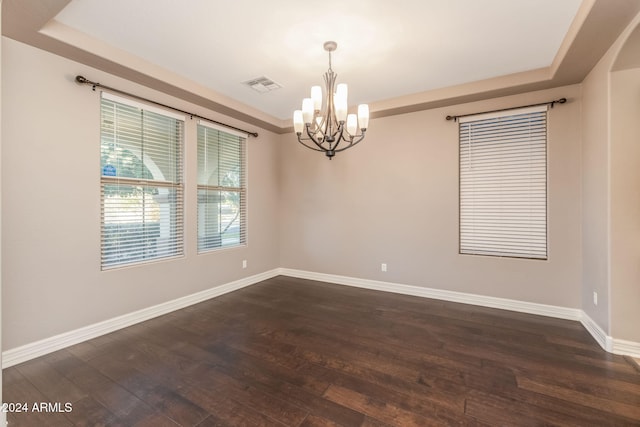 spare room with dark wood-type flooring and a notable chandelier