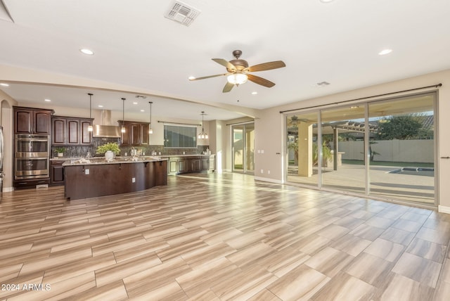 unfurnished living room featuring light hardwood / wood-style flooring and ceiling fan with notable chandelier