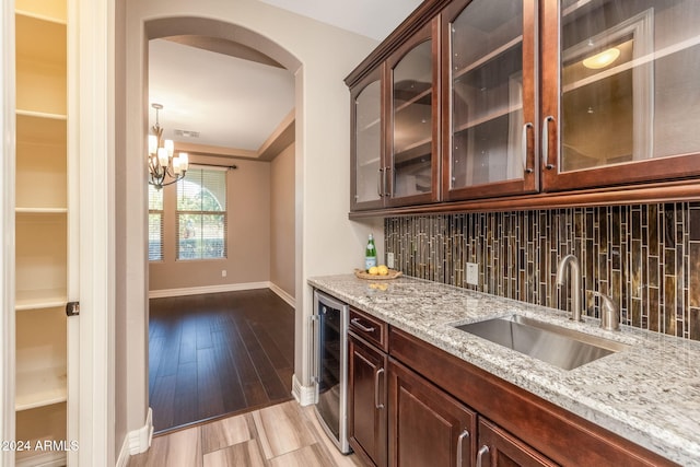 kitchen featuring dark brown cabinetry, sink, beverage cooler, tasteful backsplash, and light hardwood / wood-style floors